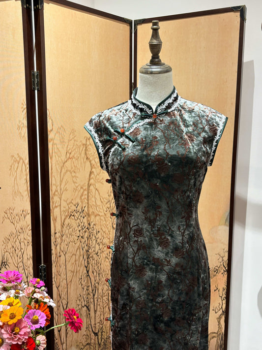 Traditional Chinese dress on a mannequin with a decorative screen and flowers in the foreground