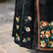 Black embroidered fabric with colorful floral and butterfly designs 