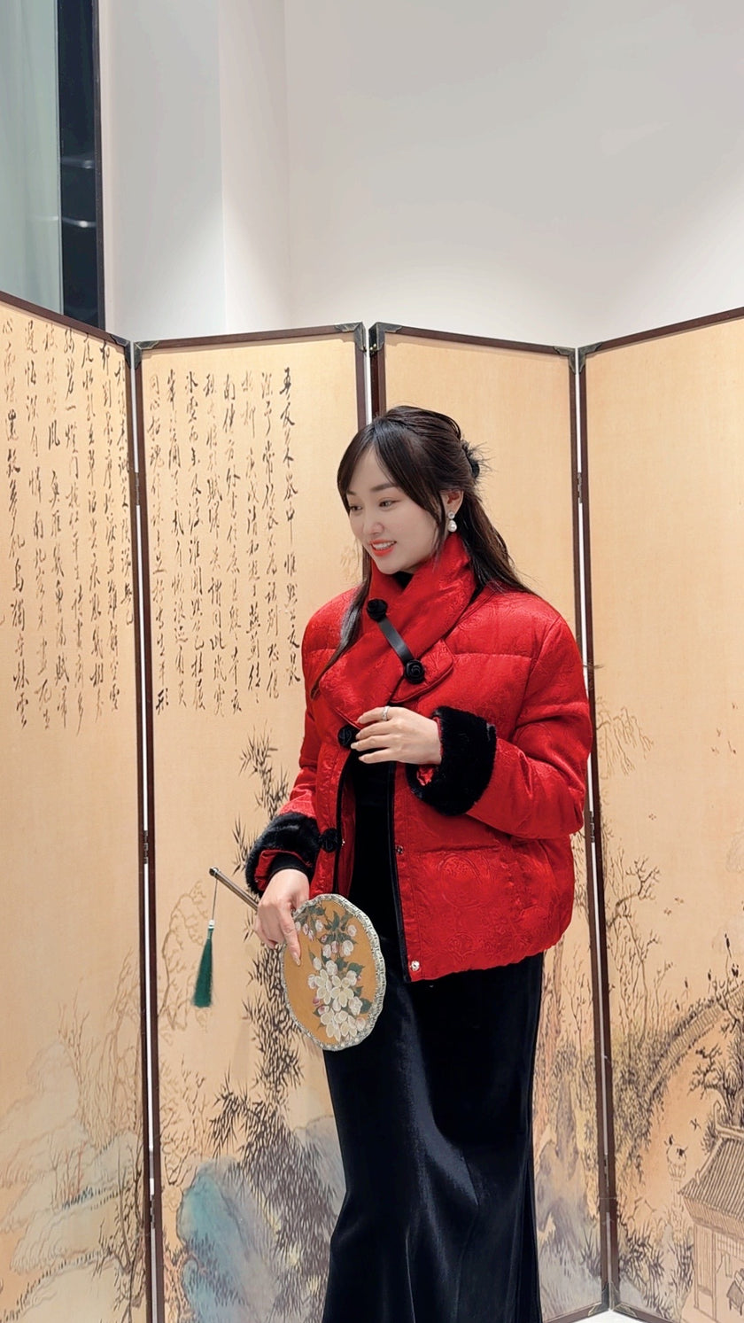 Woman in a red jacket standing in front of an ornate screen with artistic designs.