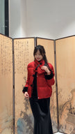 Woman in a red coat standing in front of an artistic screen