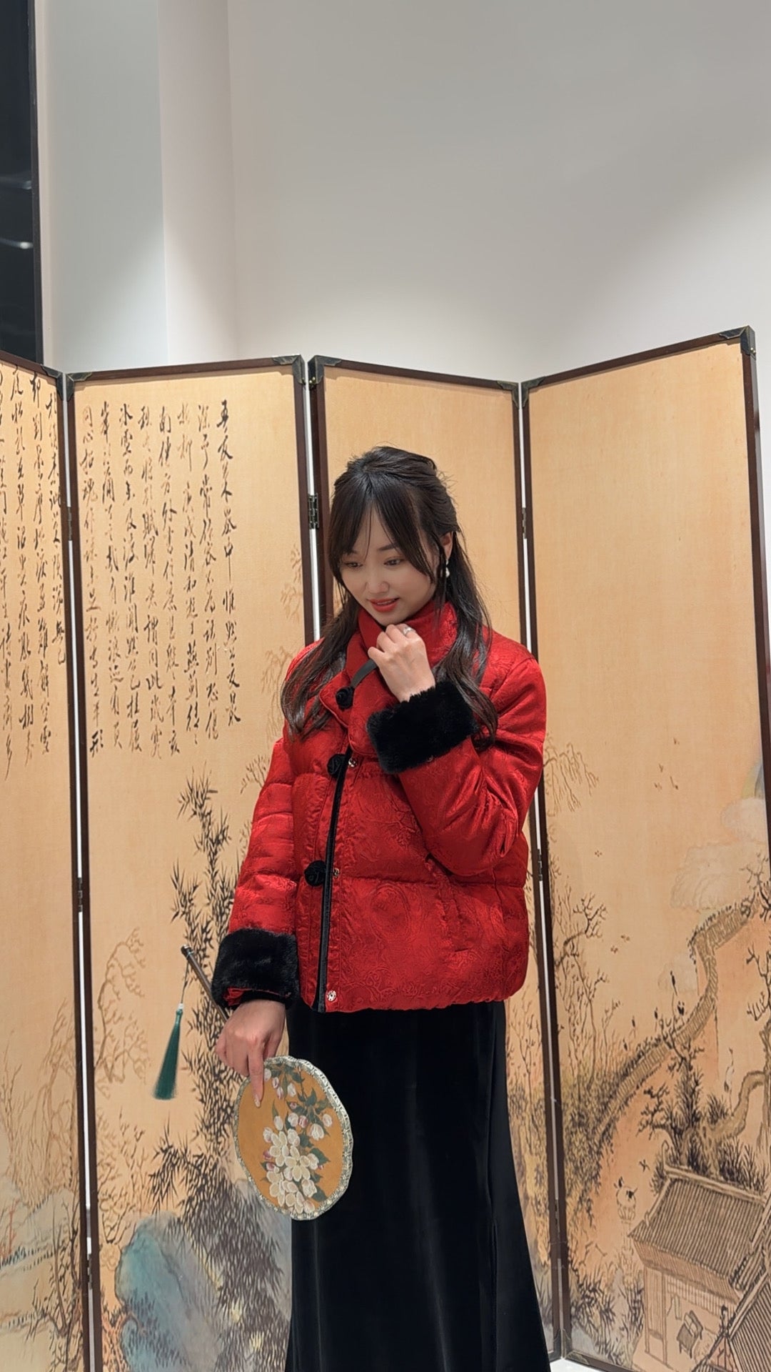 Person wearing a red puffer jacket in front of an artistic screen