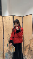 Person wearing a red puffer jacket in front of an artistic screen