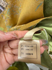 Hand holding a fabric tag with text on a piece of green fabric.