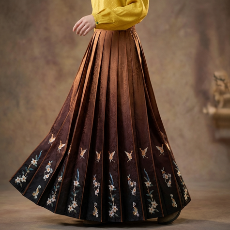 Brown pleated ma mian skirt with floral patterns worn by a person, against a neutral background
