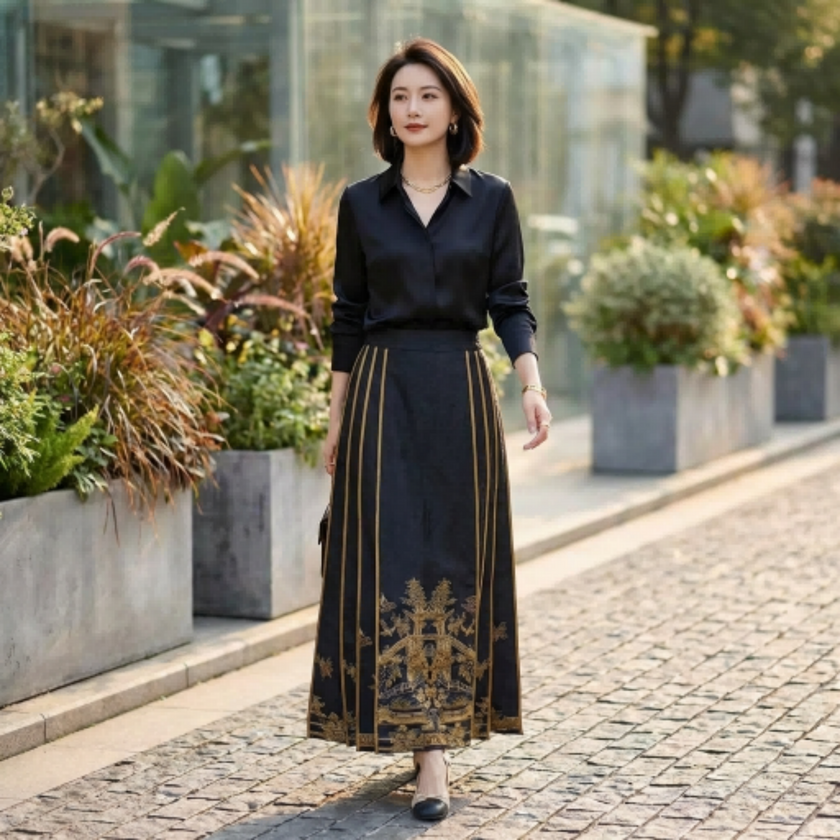 Woman in black blouse and gold patterned mamian skirt walking outdoors with plants in the background