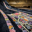 Close-up of a black fabric with colorful floral embroidery 