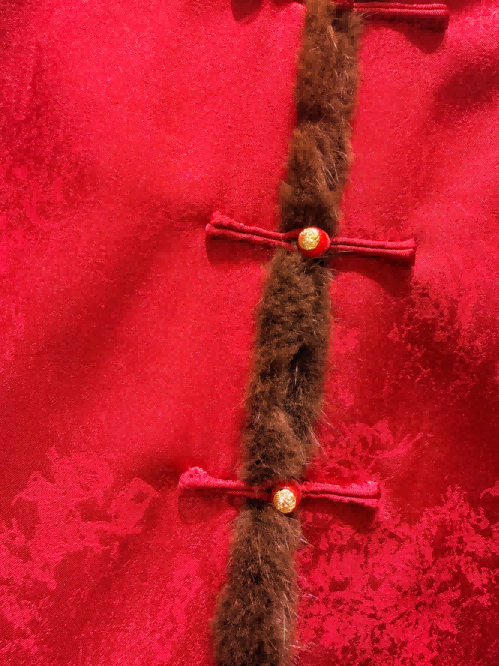 Red fabric with gold buttons and a decorative element on a red floral background