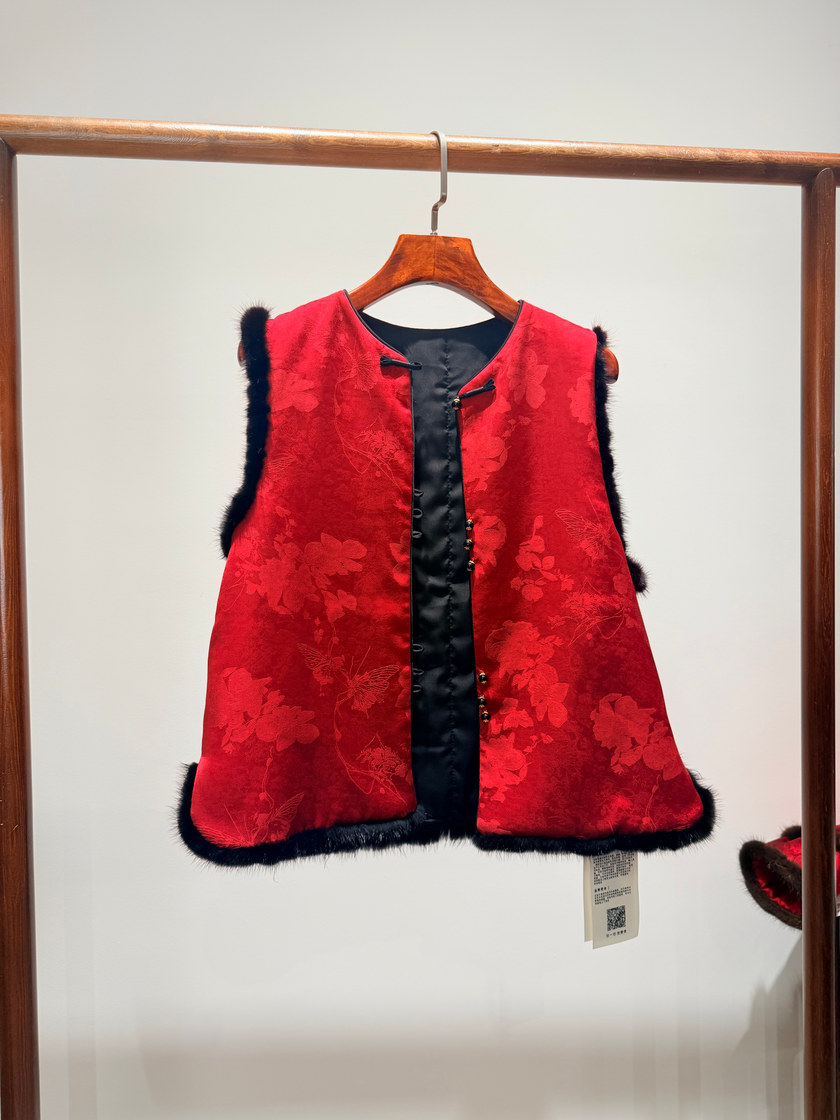 Red vest with black trim on a hanger against a white wall