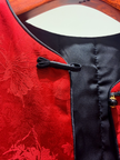 Close-up of a red garment with black floral patterns and buttons.