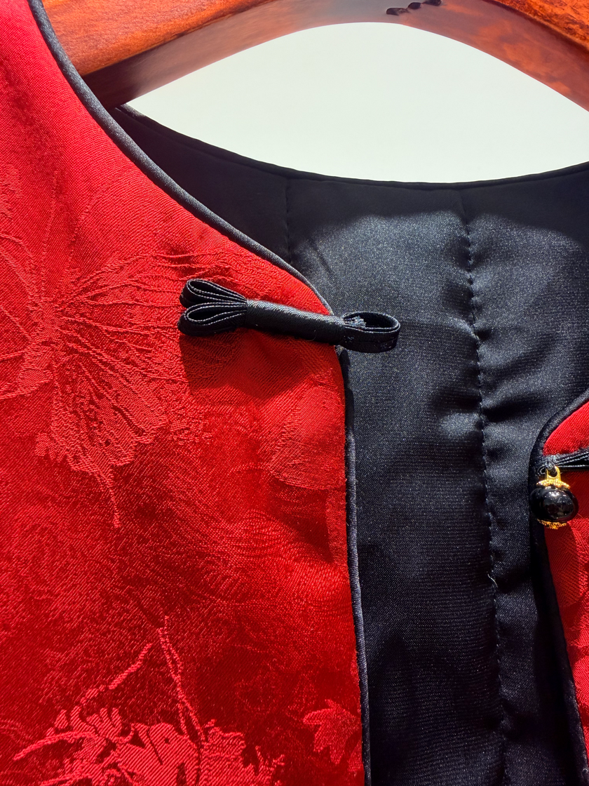 Close-up of a red garment with black floral patterns and buttons.