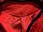 Close-up of a red garment with intricate lace detailing on a wooden surface.