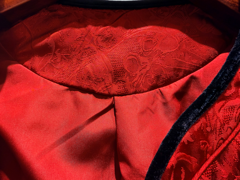 Close-up of a red garment with intricate lace detailing on a wooden surface.