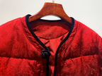 Red garment with black trim on a wooden hanger against a white background