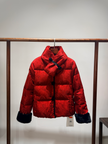 Red puffer jacket with black cuffs and collar hanging on a rack against a plain background