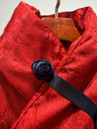 Red textured garment with a black belt and wooden hanger on a light gray background