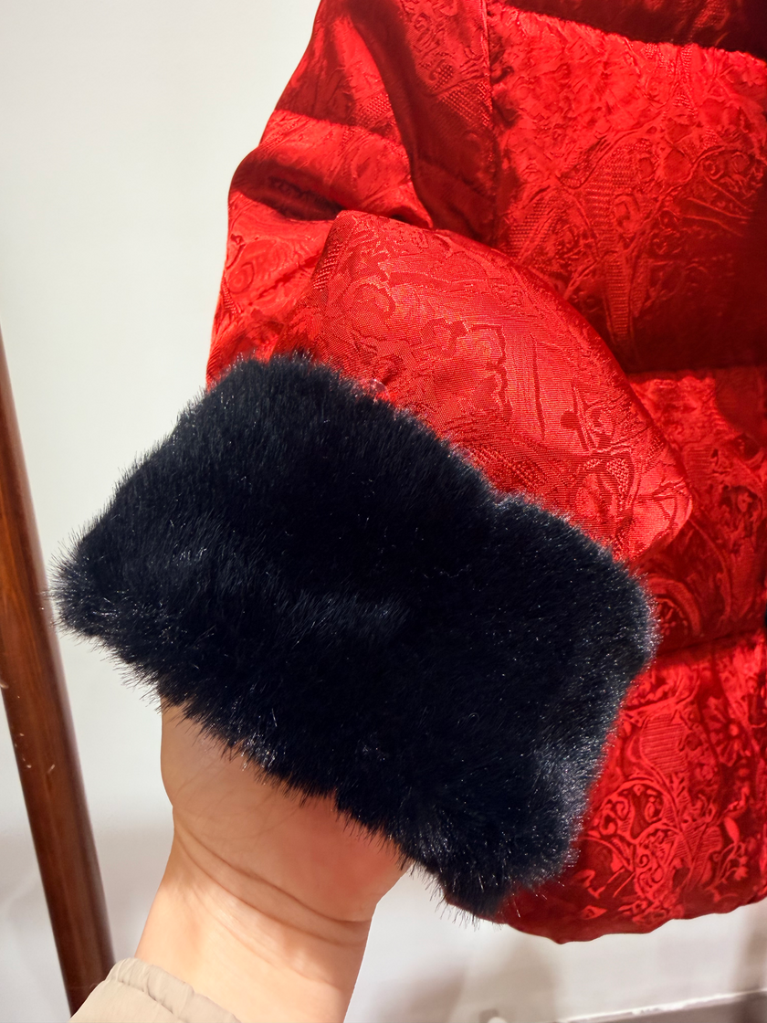 Black furry arm warmers held against a red textured background