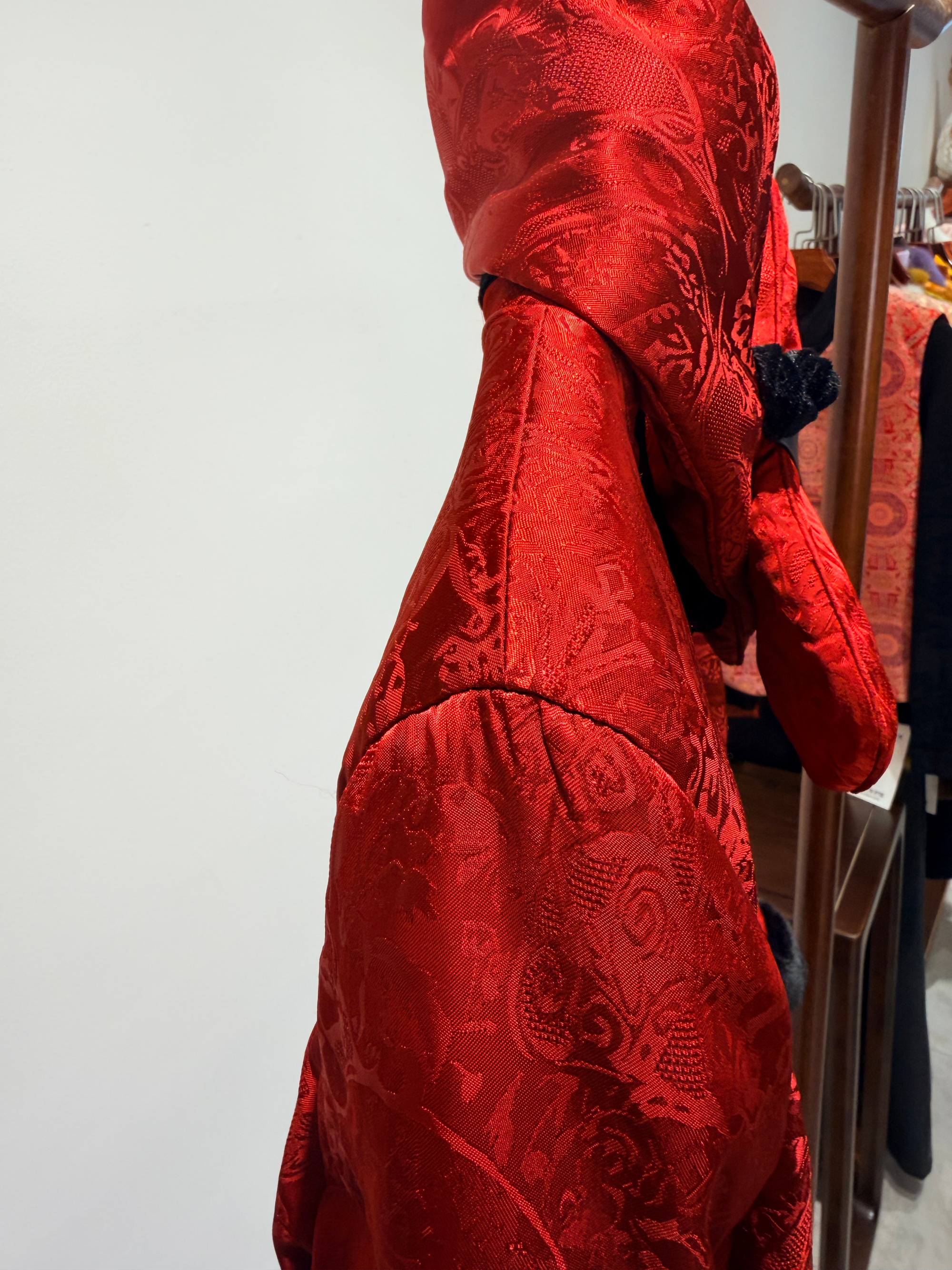 Red patterned garment on a hanger against a white wall