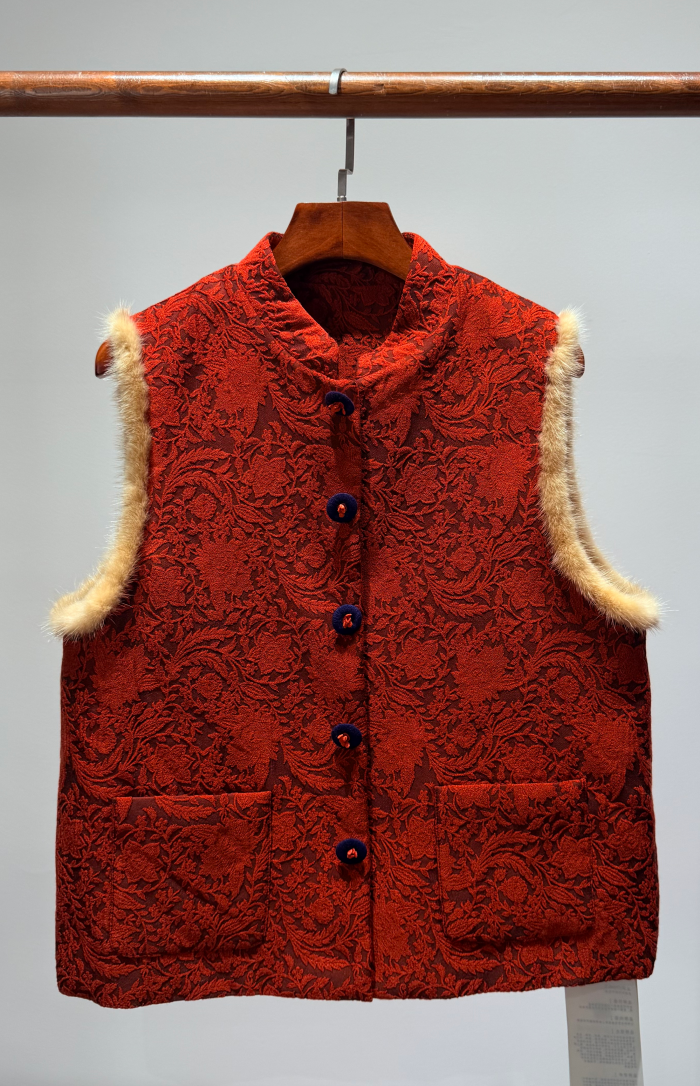 Red textured vest with fur trim on a hanger against a gray background