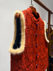 Red knitted vest with fur trim on a wooden hanger against a neutral background
