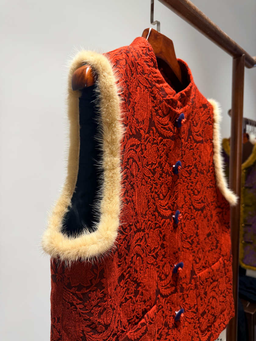 Red knitted vest with fur trim on a wooden hanger against a neutral background
