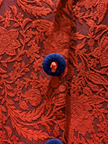Close-up of a red embroidered fabric with a blue button