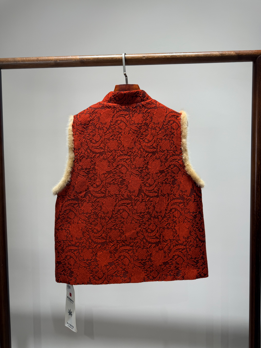 Red patterned vest with fur trim on a hanger against a gray background