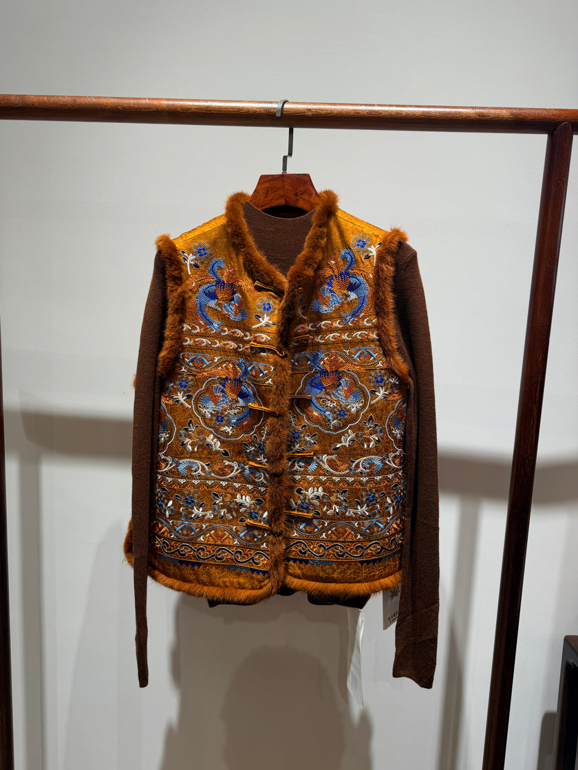 Brown patterned vest hanging on a rack against a white wall