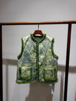 Green floral patterned vest with fur trim on a wooden hanger against a white background