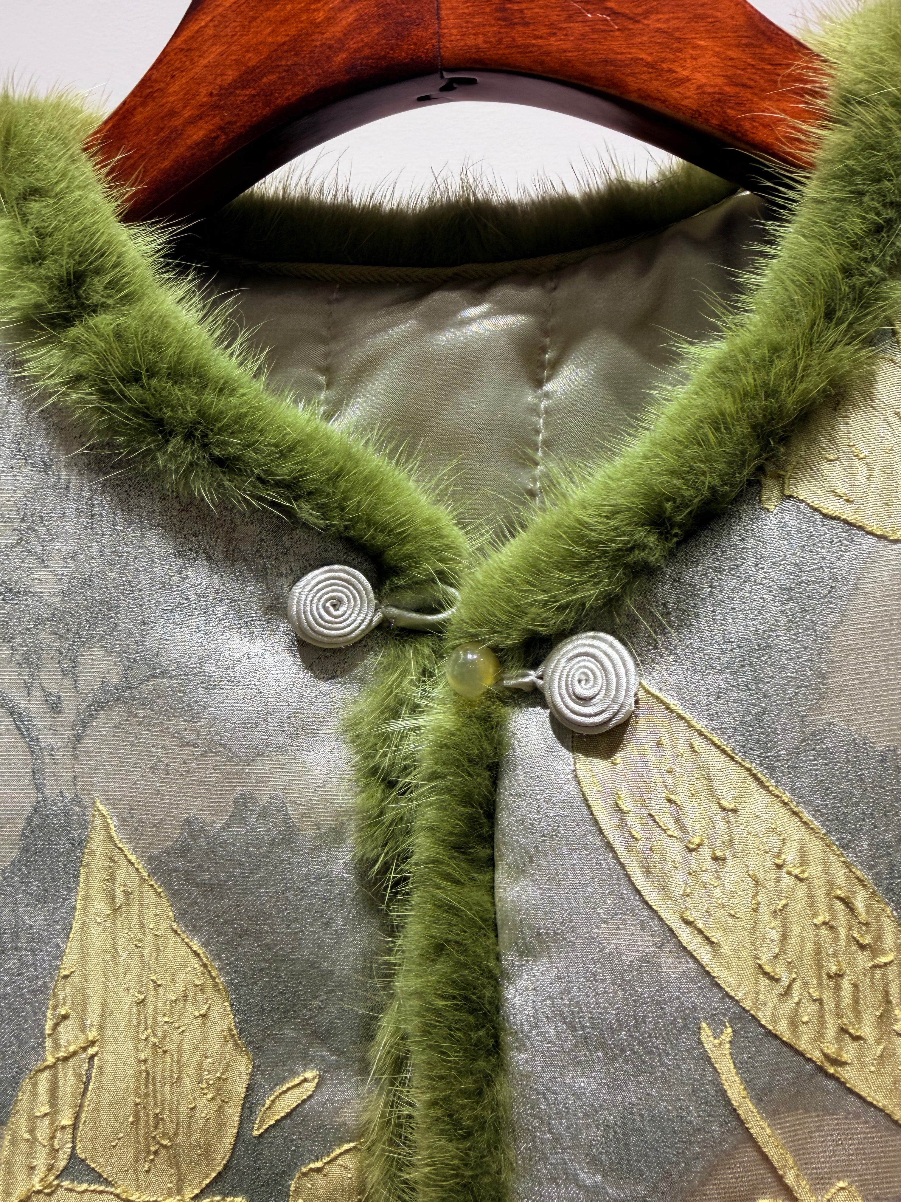 Green fur collar on a garment with gold leaf patterns