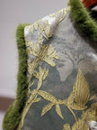 Decorative pillow with gold leaf pattern and green fur trim on a neutral background