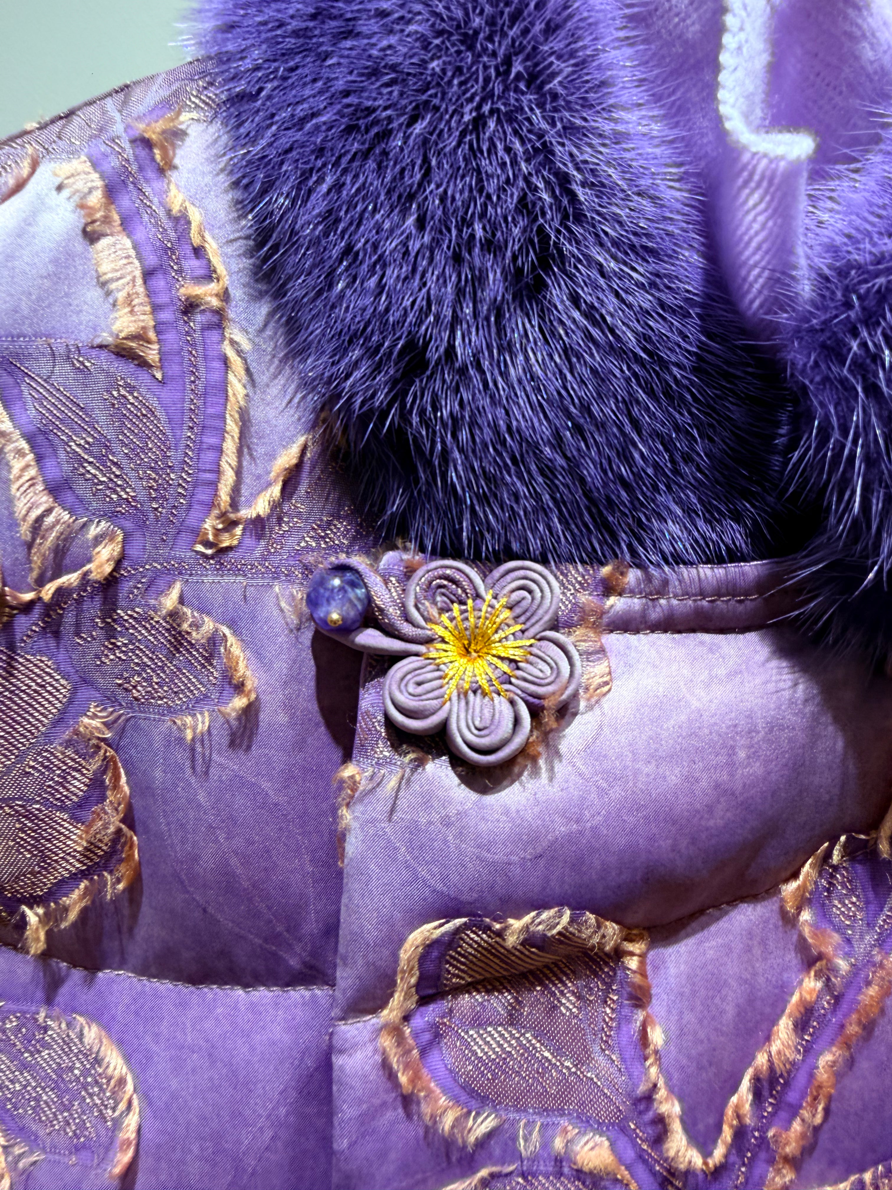 Close-up of a purple fabric with floral embroidery and decorative elements