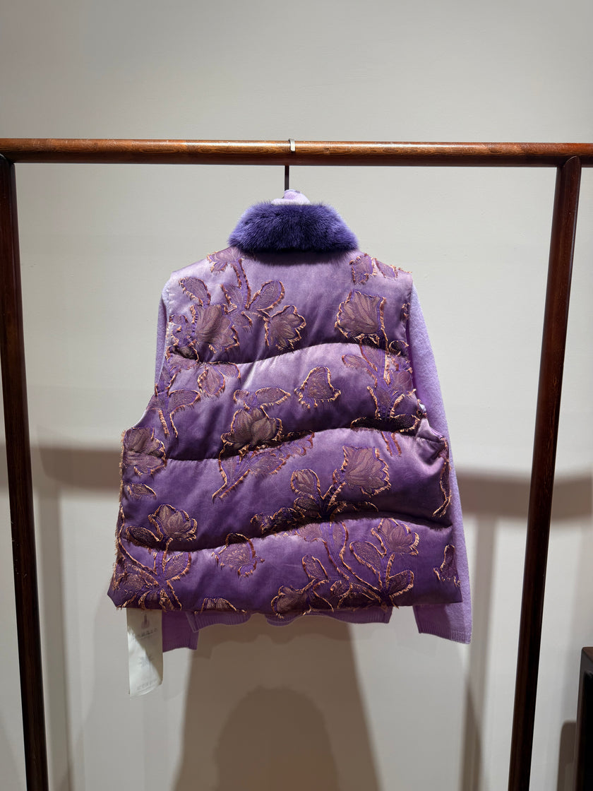 Purple embroidered vest on a wooden rack against a white wall
