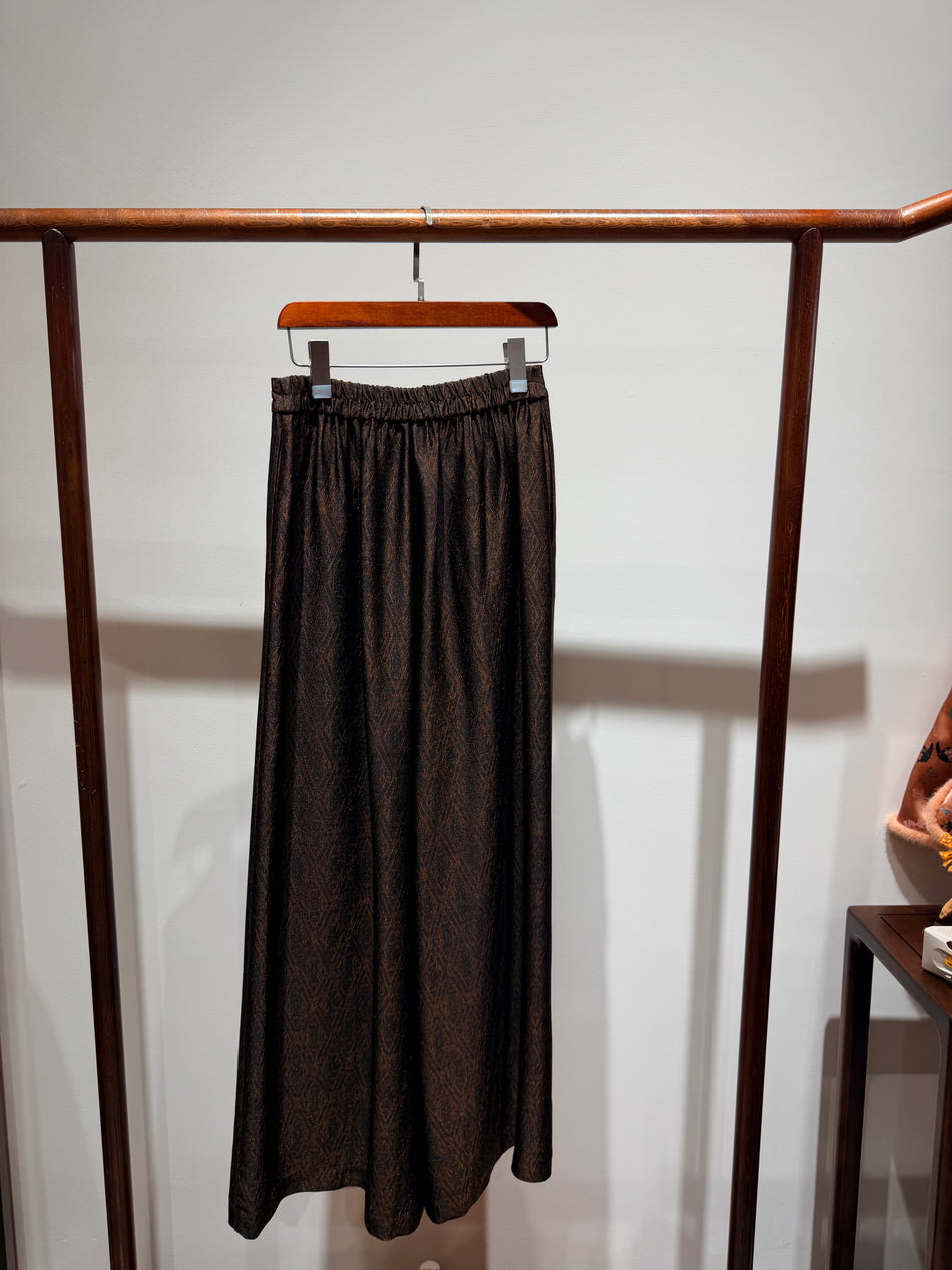 Brown skirt hanging on a wooden rack against a white wall