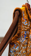 Brown embroidered garment on a hanger against a white background