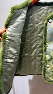 Close-up of a green quilted jacket with fur trim on a white background