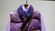 Purple patterned coat with fur collar on a hanger against a light gray background