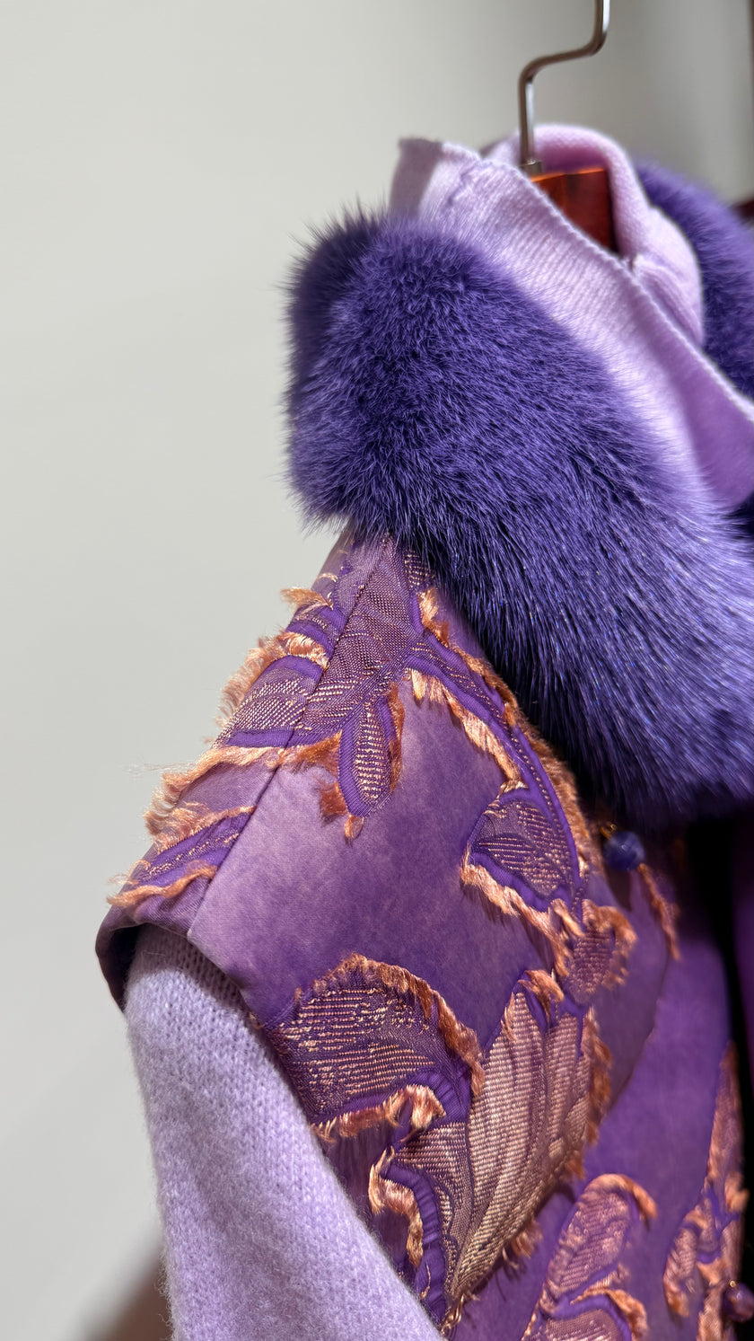 Purple garment with fur trim on a hanger against a light background