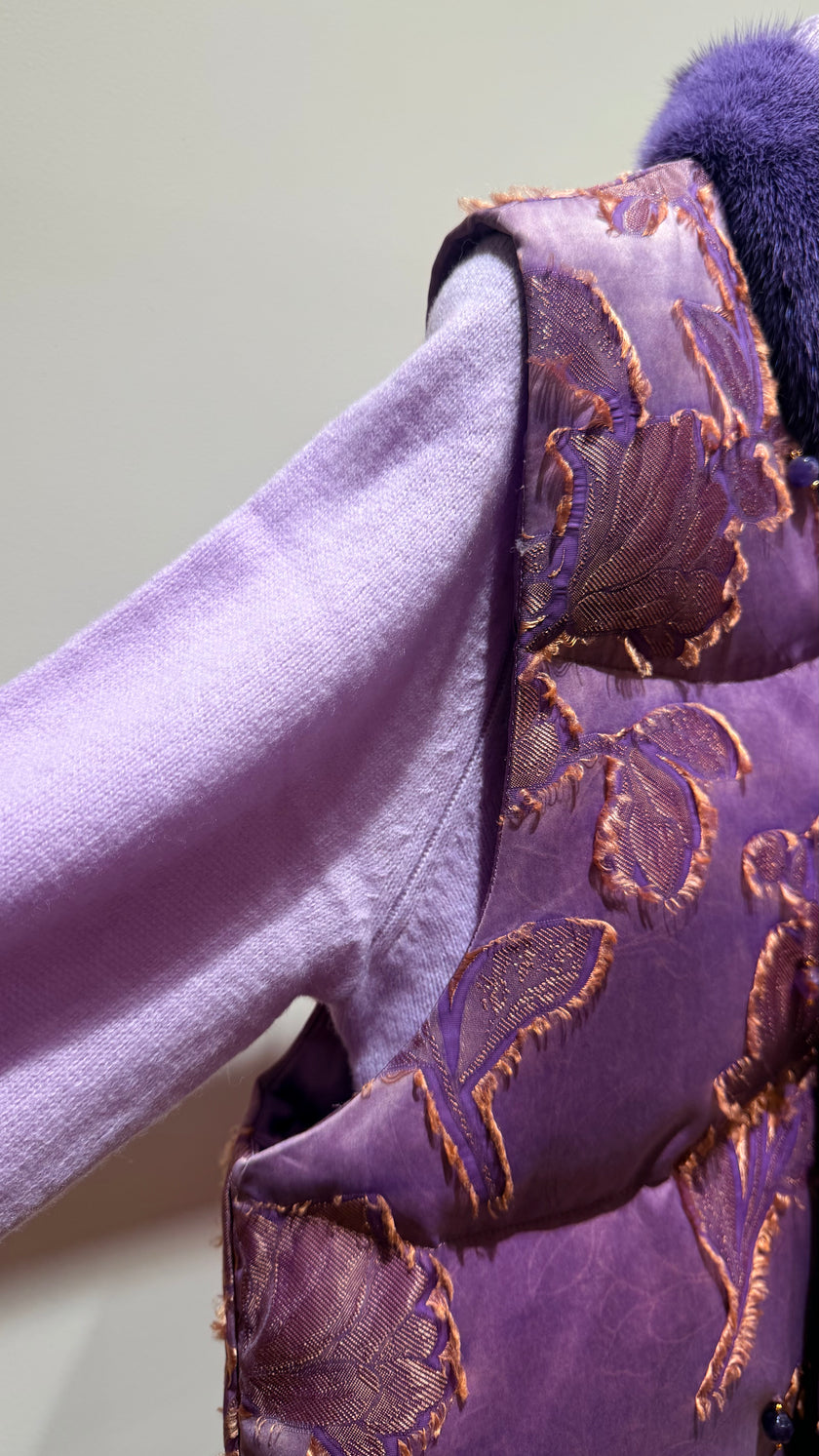 Close-up of a purple garment with floral embroidery on a light green background