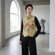 Person wearing a floral embroidered vest in a modern indoor setting