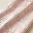Close-up of pink fabric with butterfly embroidery