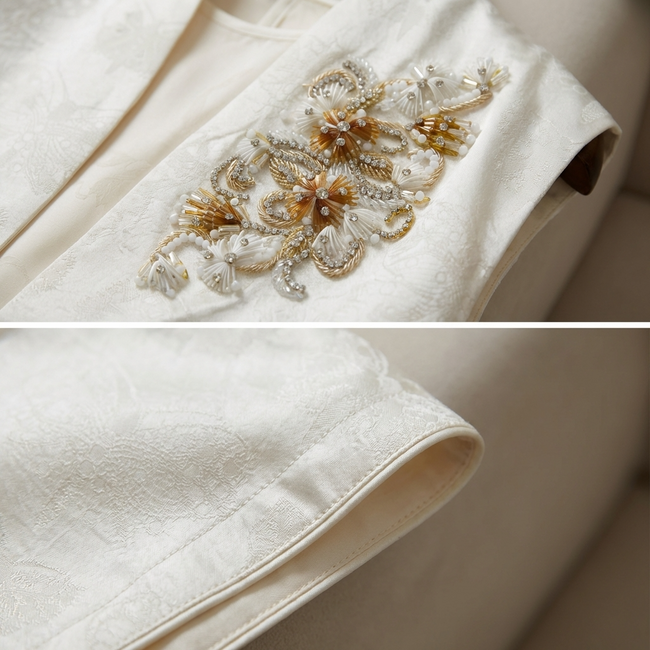 Close-up of a white vest with gold floral embroidery and fabric texture close up