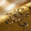 Close-up of gold fabric with intricate floral embroidery and sequins.