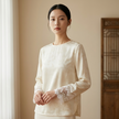 Woman wearing a white jacquard blouse with lace sleeves in a neutral setting