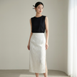 Woman wearing a black sleeveless top matching the white jacquard  skirt against a neutral background
